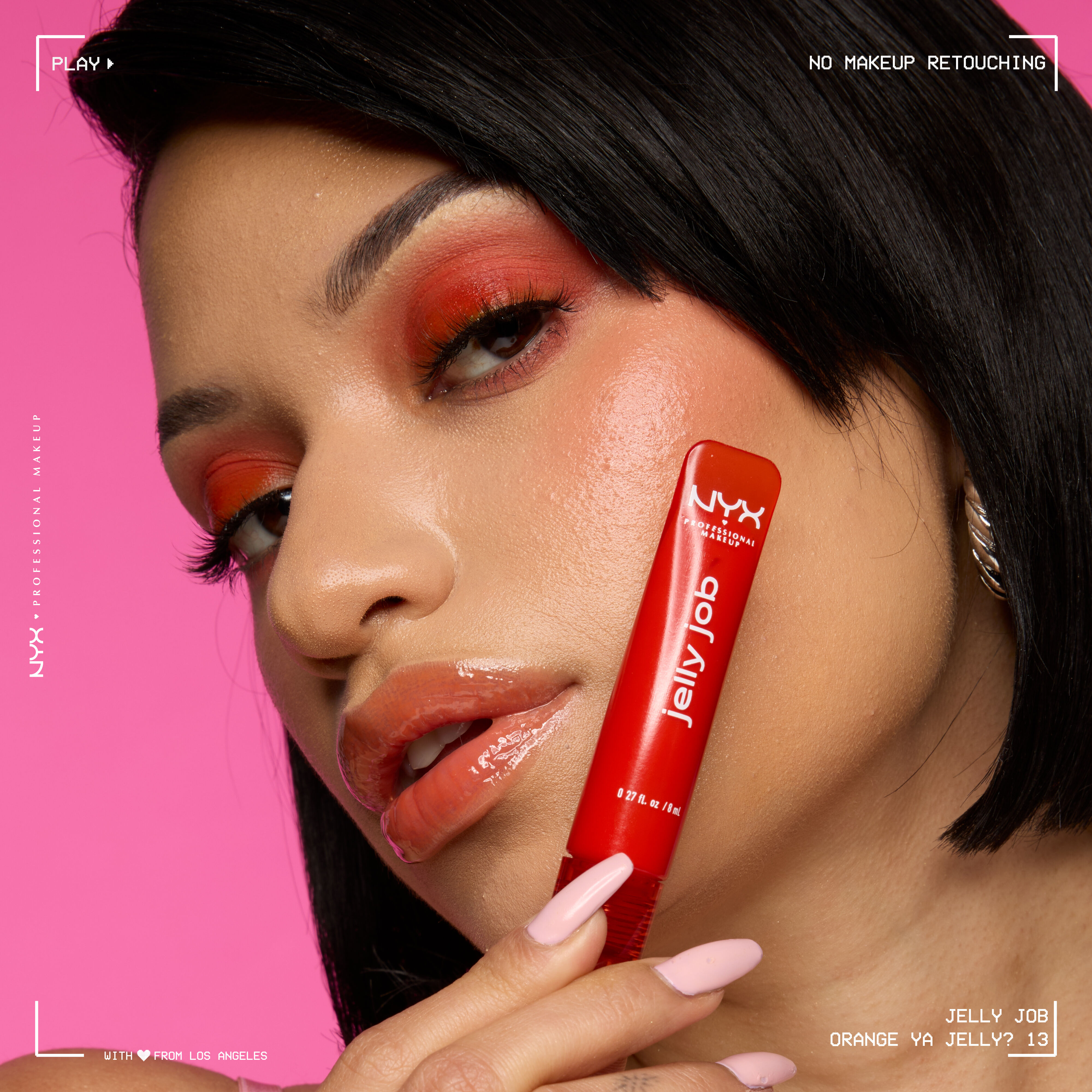 Model wearing Jelly Job Jelly Lip Gloss in shade 'Orange Ya Jelly?' and holding Jelly Job Lip Gloss