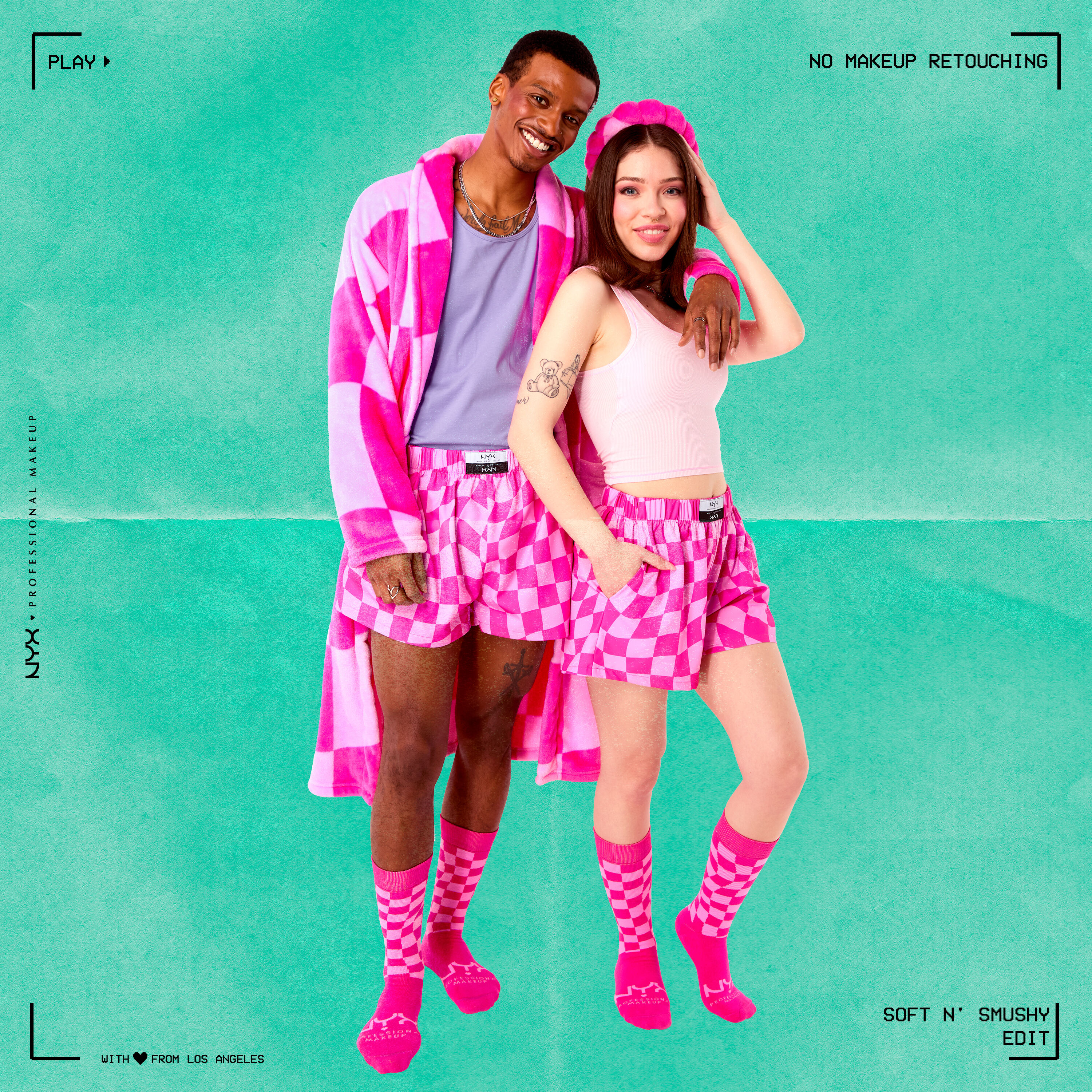 A model wearing Soft n' Smushy socks, boxers, & robe merch, with an arm around another model wearing merch socks, boxers, & a headband