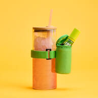 Green Lip Gloss Pouch attached to iced orange drink with straw lid