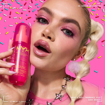 Lifestyle shot of model with dramatic pink eye makeup holding NYX Professional Makeup Suga Baddie Hair & Body Fragrance Mist pink bottle.