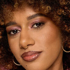 Model wearing NYX Make ’Em Wonder™ Foundation in shade 22 Medium with warm glow and gold hoop earrings.