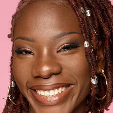 Model wearing NYX Make ’Em Wonder™ Foundation in shade 40 Walnut with radiant finish, warm undertone, and gold hoop earrings.