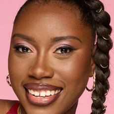 Model wearing NYX Make ’Em Wonder™ Foundation in shade 38 Deep Truffle with pink shimmer eyeshadow and glossy lips.