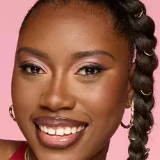 Model wearing NYX Make ’Em Wonder™ Foundation in shade 38 Deep Truffle with pink shimmer eyeshadow and glossy lips.