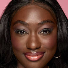 Model wearing NYX Make’em Wonder™ Foundation in shade 44 Rich Espresso with deep glow and soft coral lips.