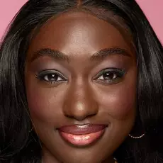 Model wearing NYX Make’em Wonder™ Foundation in shade 44 Rich Espresso with deep glow and soft coral lips.