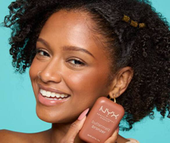 Smiling model looking at the camera and holding Buttermelt Bronzer in shade 7.5 Butta Match