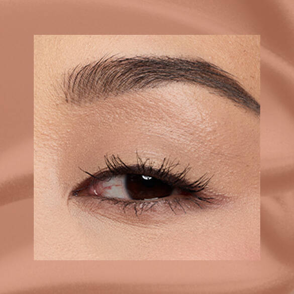 Close-up of a fair-skinned eye wearing 03 Beige Appeal, a warm beige matte cream eyeshadow from NYX Professional Makeup Lid Lingerie, on a matching beige matte backdrop.