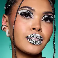 NYX Professional Makeup zebra Halloween look with white face paint, black zebra stripes, graphic eyeliner and striped lips.
