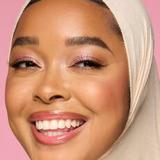 Model wearing NYX Make ’Em Wonder™ Foundation in shade 25 Warm Honey with glowing cheeks and pink shimmer eyes.