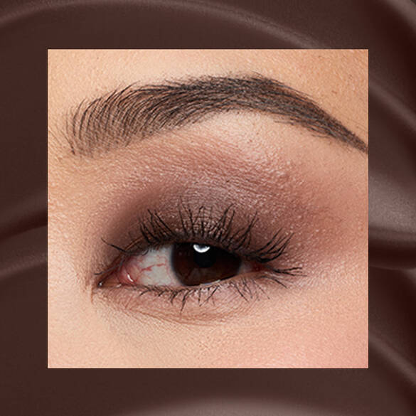 Close-up of a fair-skinned eye wearing 06 Mocha Mesh, a deep espresso matte cream eyeshadow from NYX Professional Makeup Lid Lingerie, on a matching dark-brown matte backdrop.