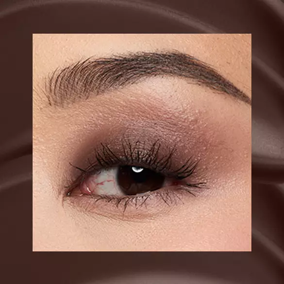 Close-up of a fair-skinned eye wearing 06 Mocha Mesh, a deep espresso matte cream eyeshadow from NYX Professional Makeup Lid Lingerie, on a matching dark-brown matte backdrop.