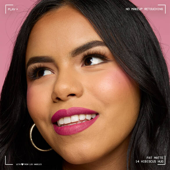 Close-up of model with medium skin tone wearing NYX Professional Makeup Fat Matte Smooth Color Lipstick in Hibiscus Hug, a magenta shade, showing a smooth, non-cakey matte finish. No makeup retouching.