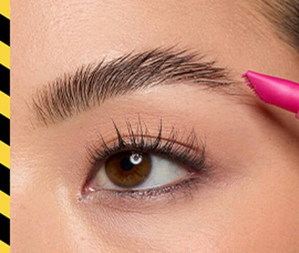 Closeup of model combing tail hair of eyebrow out using The Brow Glue Crazy Lift