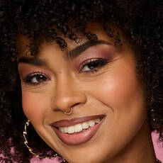 Model wearing NYX Make ’Em Wonder™ Foundation in shade 17 Medium Olive with peach blush and neutral lip gloss.