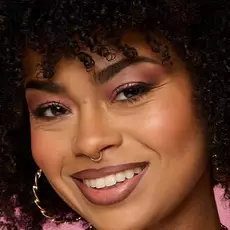 Model wearing NYX Make ’Em Wonder™ Foundation in shade 17 Medium Olive with peach blush and neutral lip gloss.