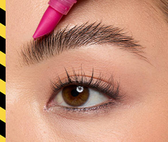 Closeup of model combing eyebrow hair upward with The Brow Glue Crazy Lift
