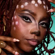 NYX Professional Makeup warm-toned Halloween look with peach makeup, red and purple cheek marks, defined brows and nude lips.