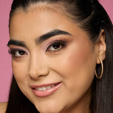 Model wearing NYX Make ’Em Wonder™ Foundation in shade 15 Buff with radiant soft matte finish and gold hoops.