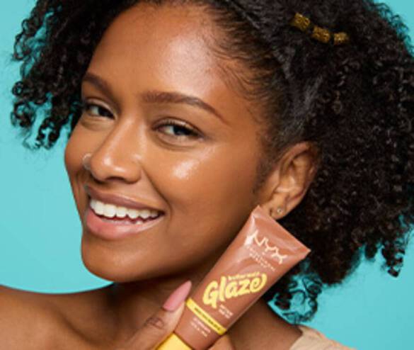 Smiling model looking at the camera and holding Buttermelt Glaze Tint in shade 06 Praline Butta