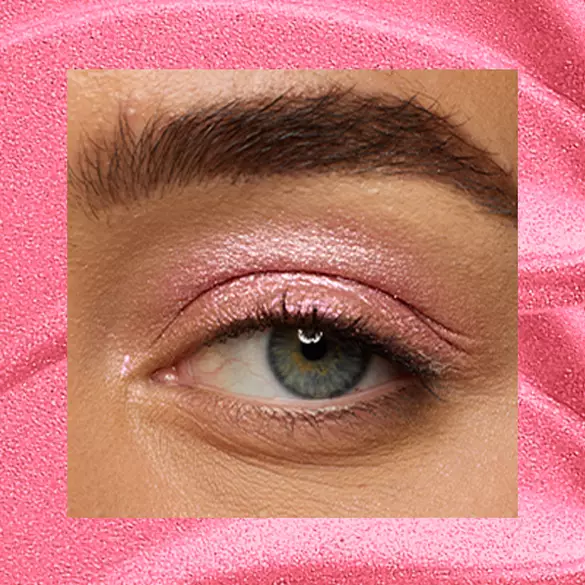 Close-up of a fair-skinned eye wearing 08 Push-Up Pink, a bubblegum-pink metallic cream eyeshadow from NYX Professional Makeup Lid Lingerie, on a matching pink shimmer backdrop.