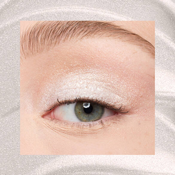 Close-up of a fair-skinned eye wearing 01 Satin Silver, an ice-white metallic cream eyeshadow from NYX Professional Makeup Lid Lingerie, on a matching silver shimmer backdrop.