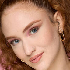 Model wearing NYX Make ’Em Wonder™ Foundation in shade 02 Fair Porcelain with pink eyeshadow and glossy nude lips.