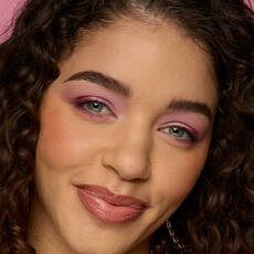 Model wearing NYX Make ’Em Wonder™ Foundation in shade 14 True Beige with pink eye makeup and glossy lips.