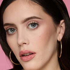 Model wearing NYX Make ’Em Wonder™ Foundation in shade 04 Cool Porcelain with soft pink blush and gold hoop earrings.