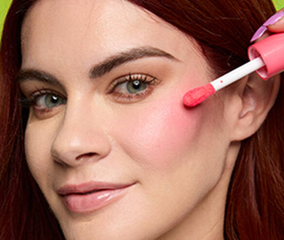 Closeup of woman applying Fat Cheeks Juicy Blush to cheek with applicator