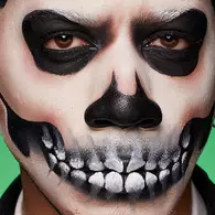 NYX Professional Makeup Halloween skull look with blackened eye sockets, skeletal nose detail and painted teeth across the mouth.