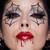 NYX Professional Makeup spider Halloween look with white face paint, black spiderweb eyes, red blood-effect lips and a spider detail on the forehead.