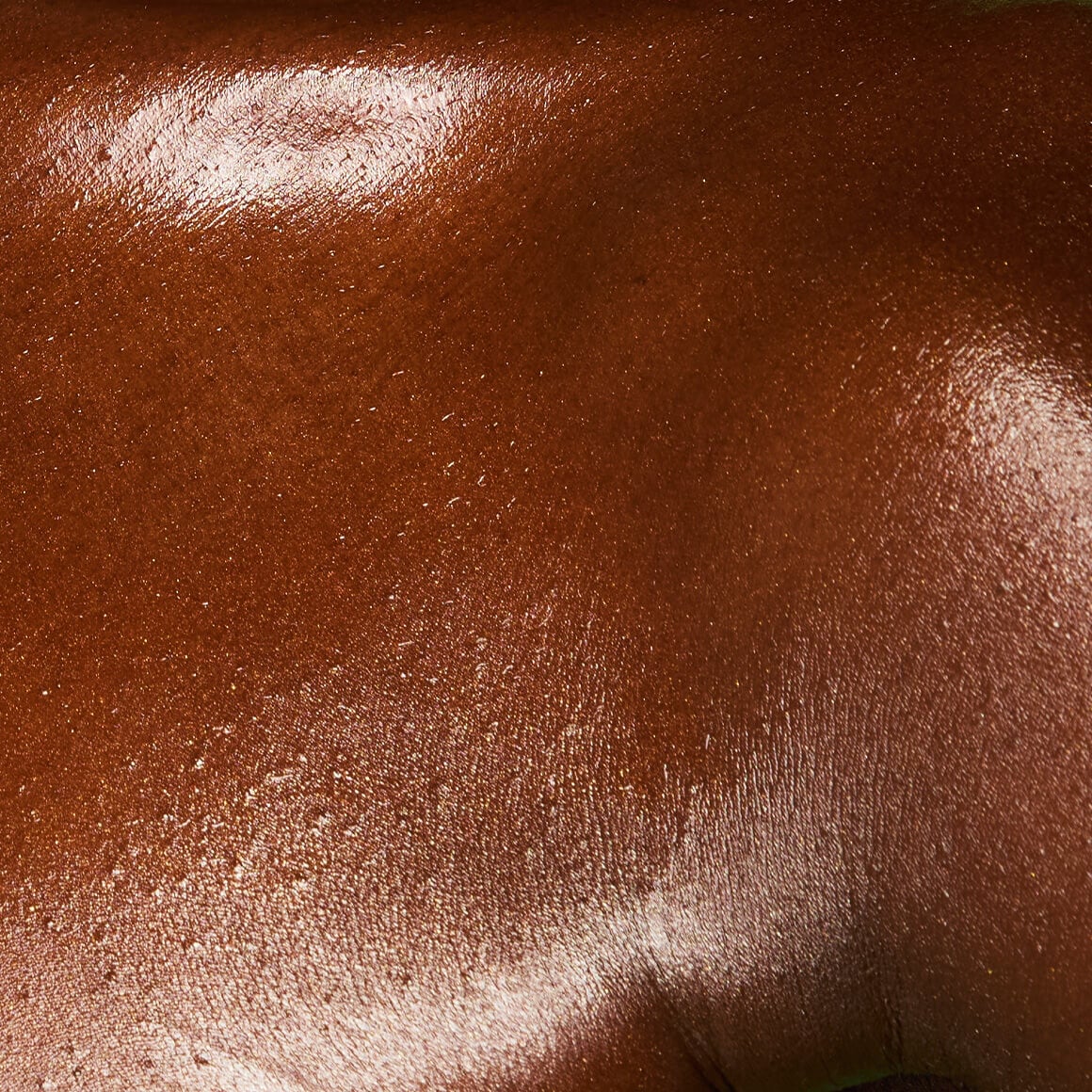 Image of the model’s chest after applying NYX Professional Makeup Fat Oil Body Oil in Caramelt Mami, showing a gold, bougie finish.